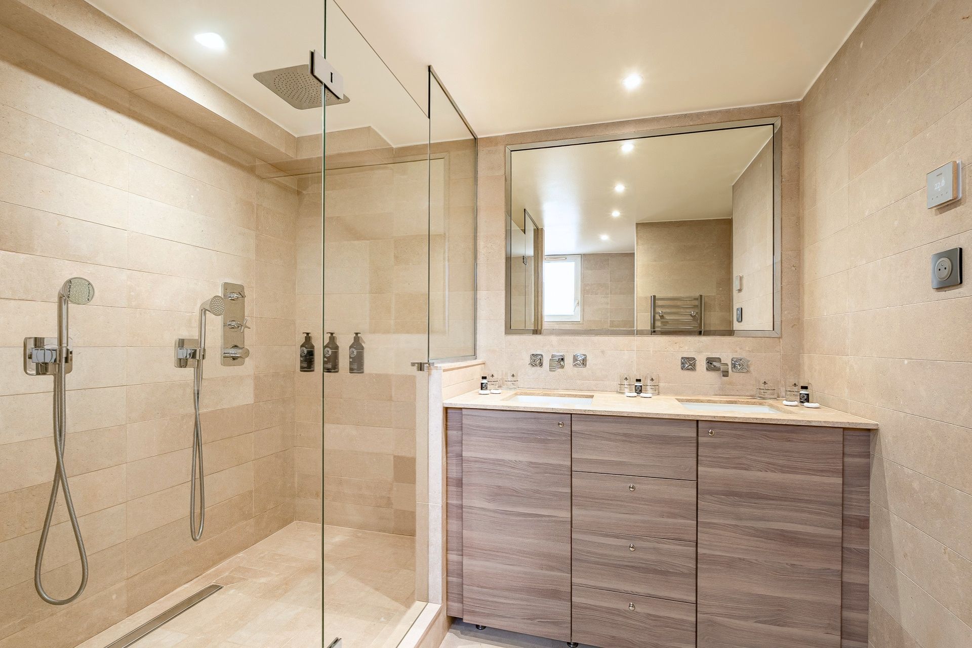 Ein modernes Badezimmer mit einer Duschkabine aus Glas, einem großen Spiegel und einem Holzboden mit Waschbecken.