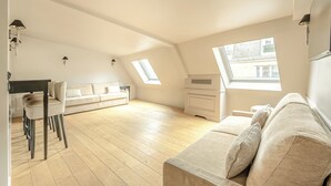 A spacious loft apartment with a high ceiling, a wooden floor, a sofa, a dining table, and two skylights. - Hotel Résidence Des Arts - Saint-Germain (Paris)