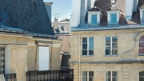 Un edificio de varios pisos con una mezcla de estilos arquitectónicos, que presenta balcones con barandillas de hierro forjado y una variedad de diseños de ventanas.