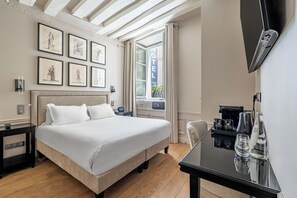A hotel room with a bed, bedside tables, a desk with a coffee machine, and framed artwork on the wall. - Hotel Résidence Des Arts - Saint-Germain (Paris)