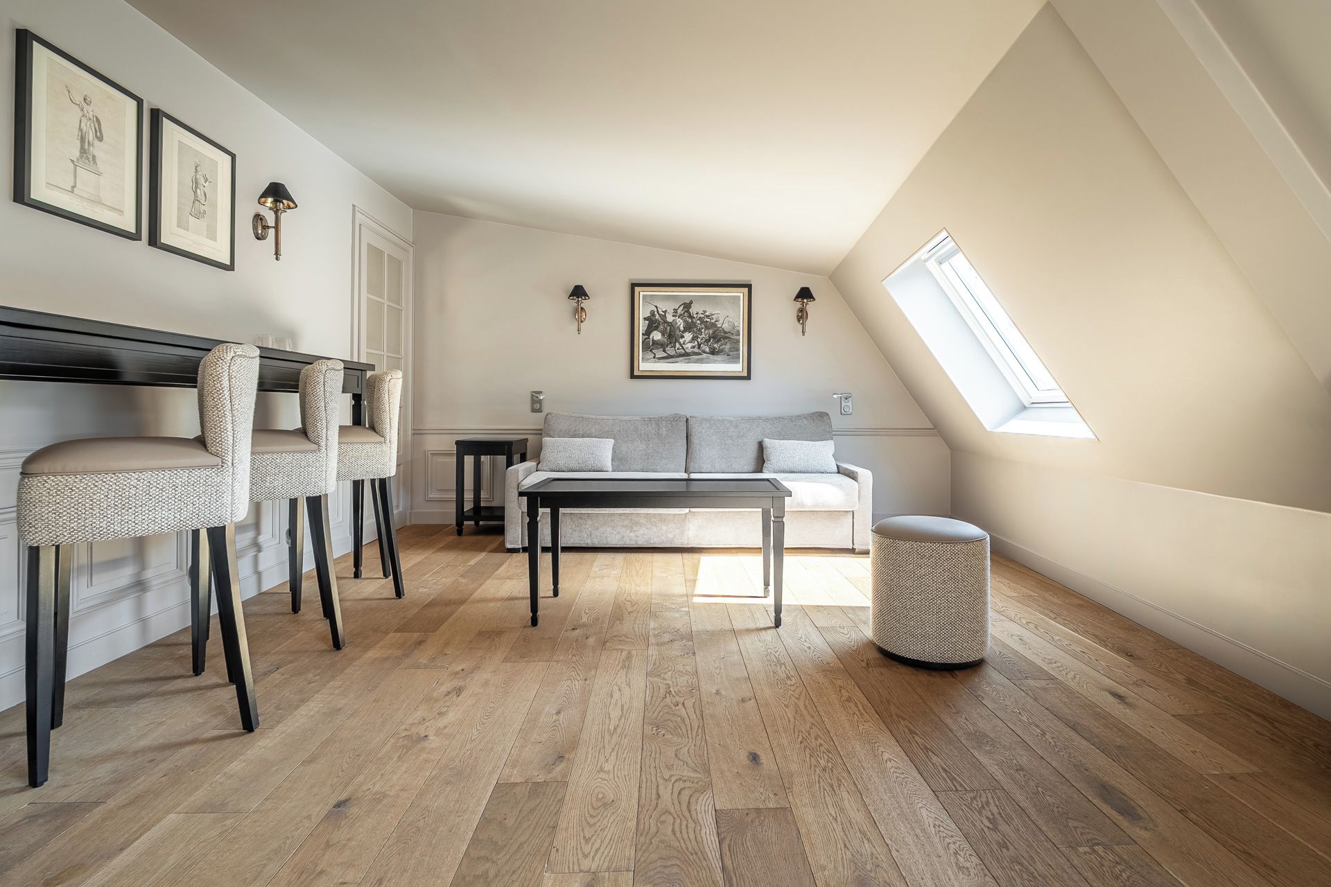 Un dormitorio tipo loft con techo inclinado, un sofá, una mesa de comedor y dos sillas.