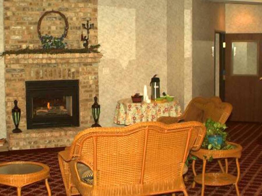 Una sala de estar con chimenea, muebles de mimbre, televisor y espejo.