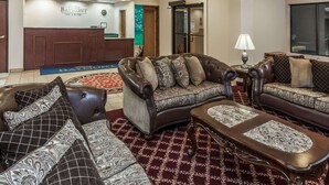 A hotel lobby with leather sofas, a reception desk, and a large window. - Baymont by Wyndham New Buffalo (New Buffalo)