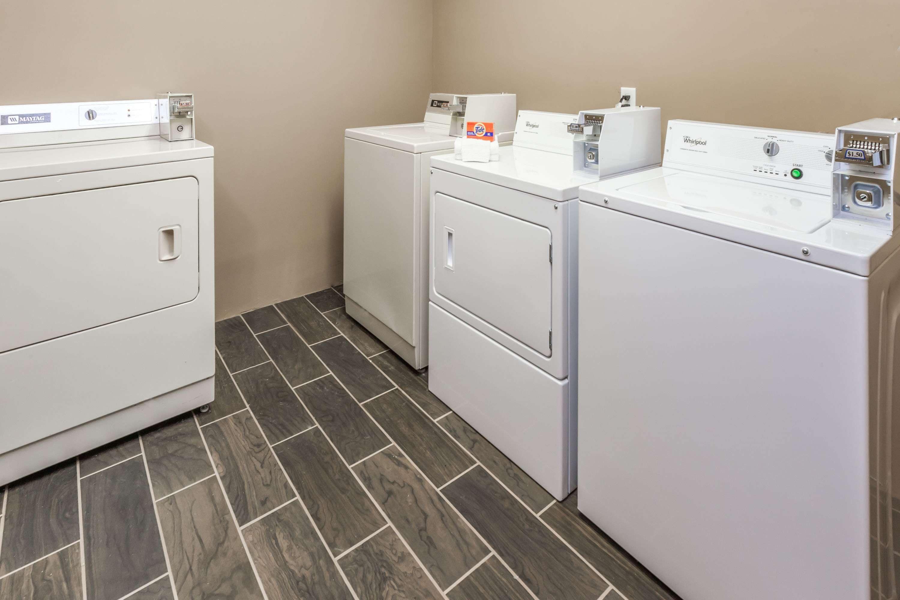 A laundry room with two front-loading washing machines and a dryer.