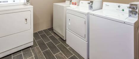 A laundry room with two front-loading washing machines and a dryer.