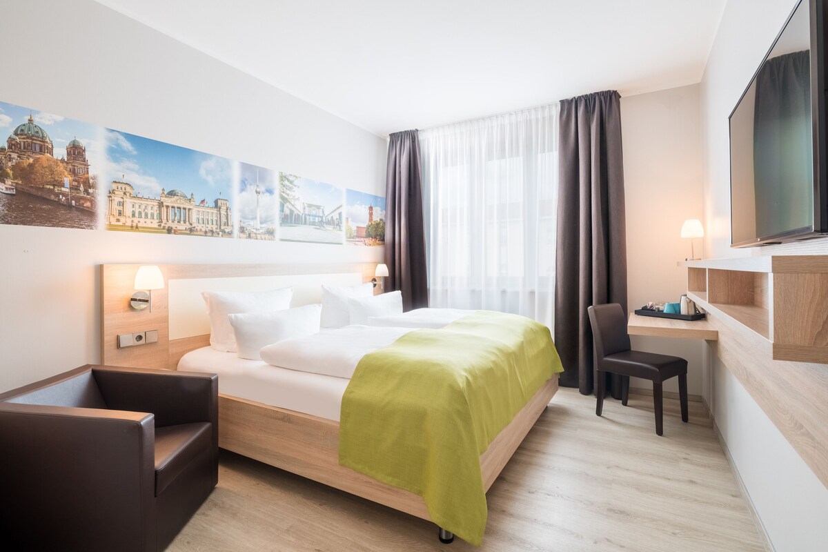 Une chambre d’hôtel moderne équipée d’un lit, d’un bureau, d’une chaise et d’un téléviseur.