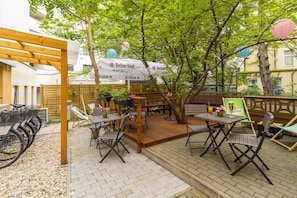 Een terras met tafels en stoelen, omringd door bomen en overdekt door een luifel.
