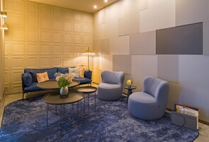 Ein stilvoller Lounge-Bereich mit einer Couch, Sesseln, einem Couchtisch und einer Lampe.