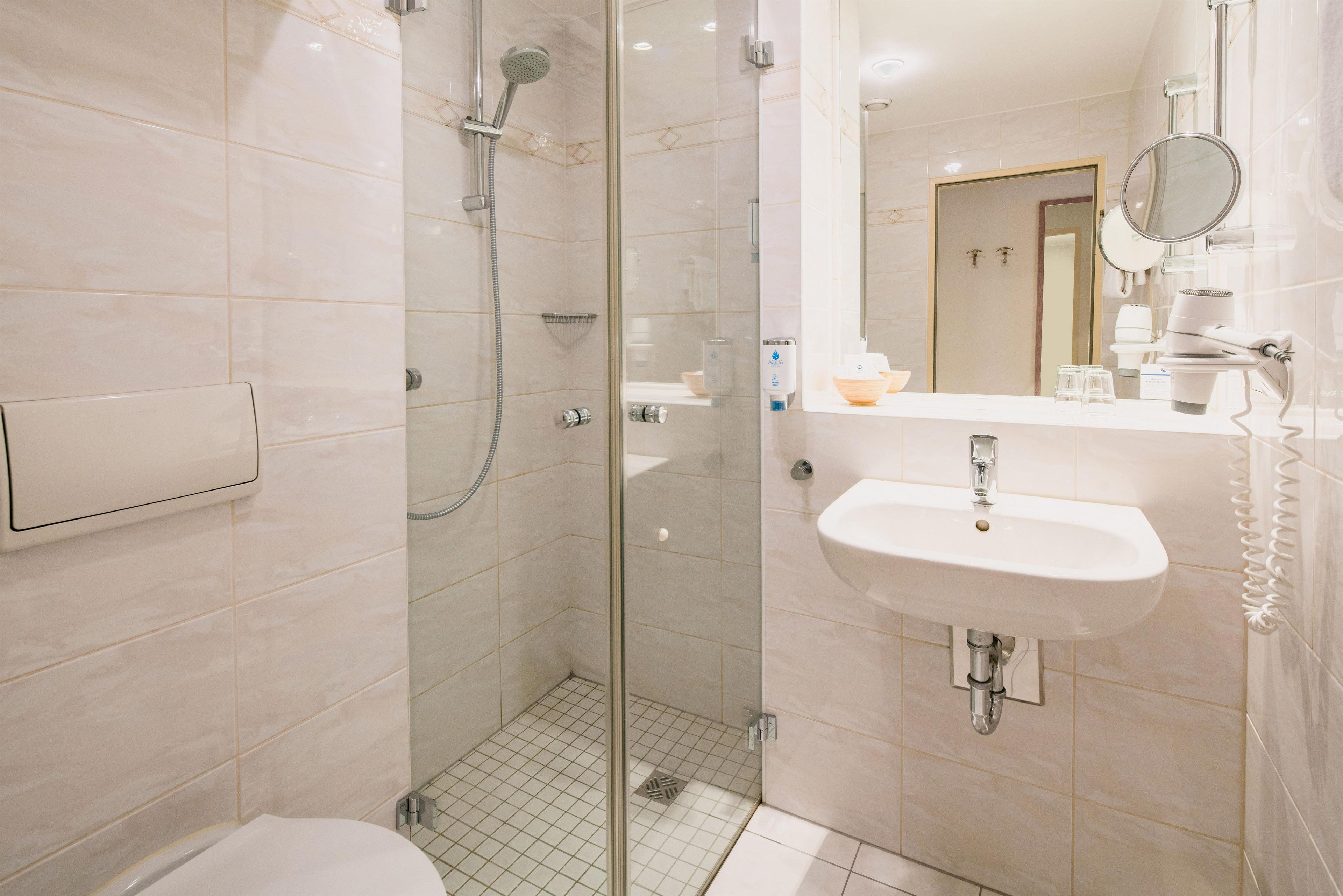 A modern bathroom with a glass-enclosed shower, a white sink, and a mirror above it.