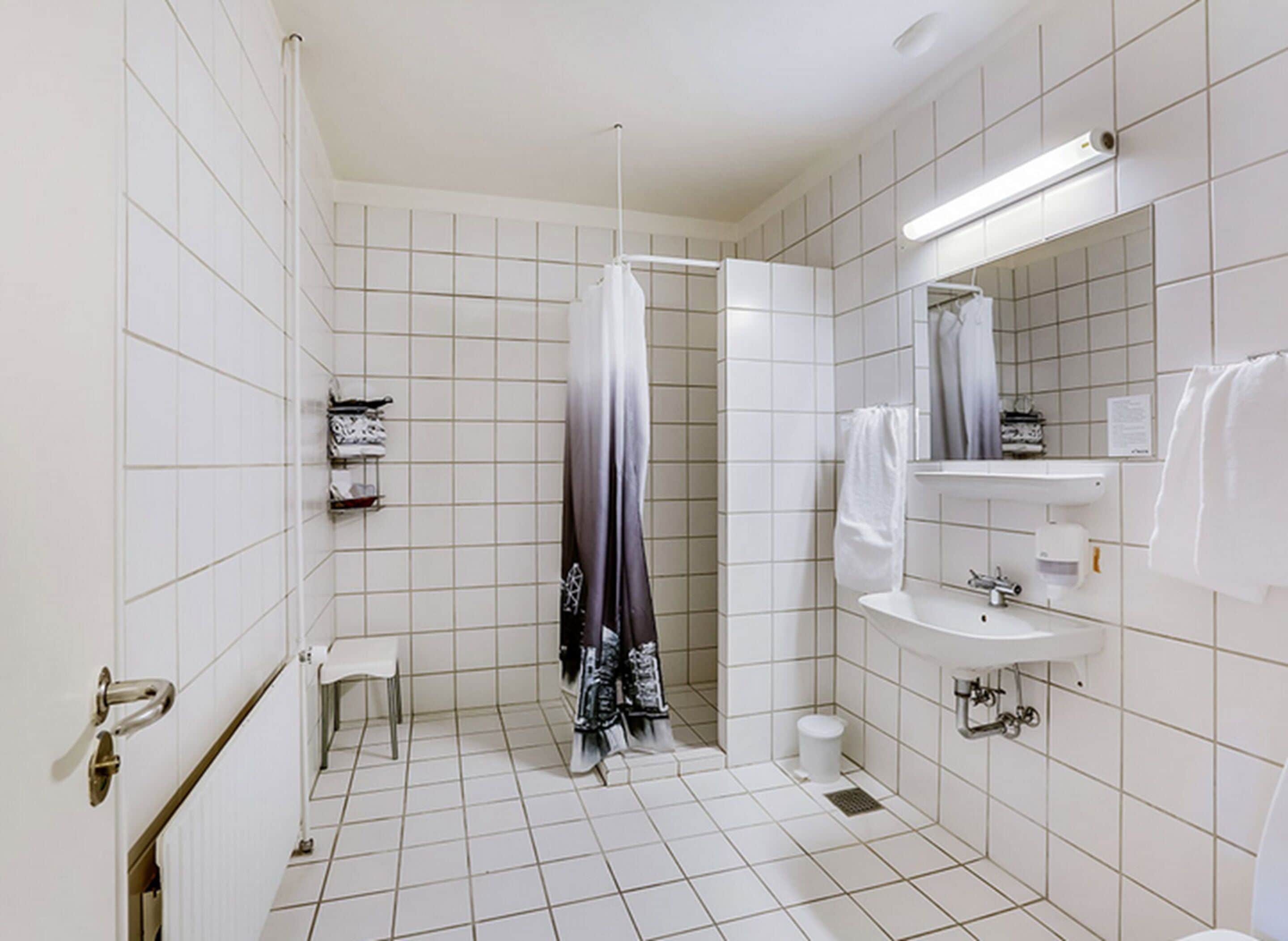 A modern bathroom with a shower, toilet, sink, and a small vanity with a mirror.
