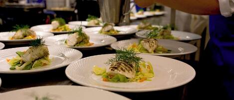 A chef preparing dishes in a professional kitchen with multiple plates of food on the counter.