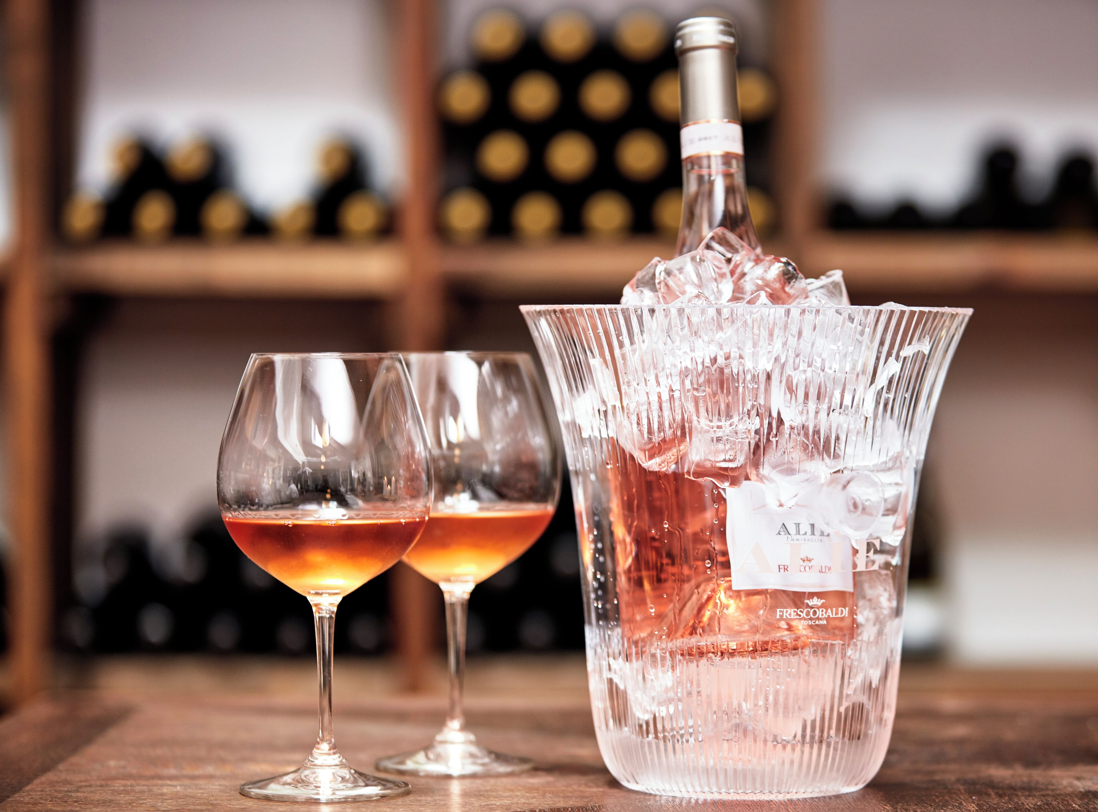 Una botella de vino y dos copas sobre una mesa de madera.