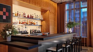 Un bar moderne doté d’un long comptoir, de plusieurs étagères remplies de bouteilles d’alcool et d’un espace salon avec des chaises et une table.