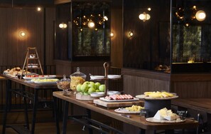 A buffet with various food items, a ladder, and a view of the outdoors through large windows.