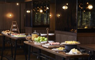 En buffet med forskellige spiser, en stige og udsigt til det fri gennem store vinduer.