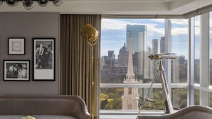 Un salon moderne avec vue sur la ville, comprenant un canapé, une table basse et un lampadaire.