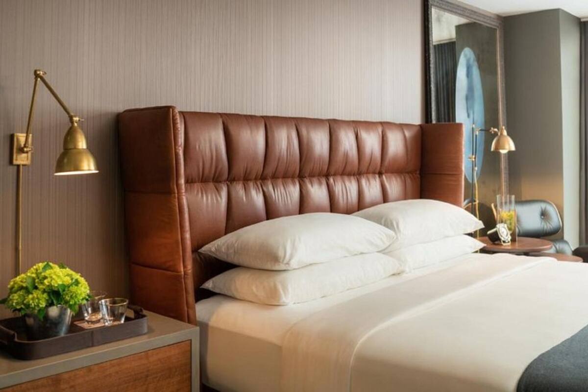 A hotel room with a large bed, a nightstand with a lamp, and a mirror.