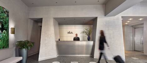 A modern reception area with a marble floor, a reception desk, and a large potted plant.