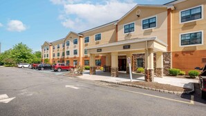 A multi-story hotel with a covered entrance, a parking lot, and a clear sky.