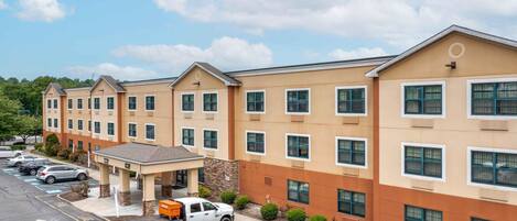 A multi-story hotel with a parking lot, a covered entrance, and a truck parked outside.