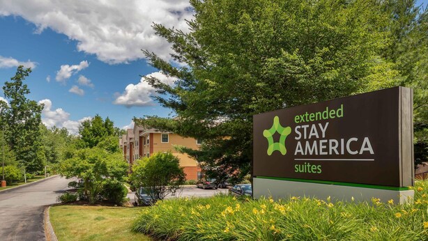 Een bord voor Extended Stay America suites, met een helder zicht op het omliggende groen en een gebouw op de achtergrond.