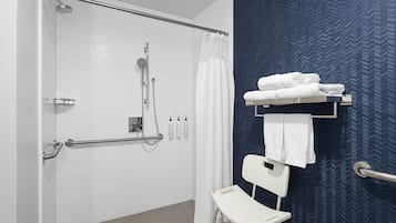Kylpyhuone, jossa on suihku, valkoinen tuoli ja pyyheteline pyyhkeineen.