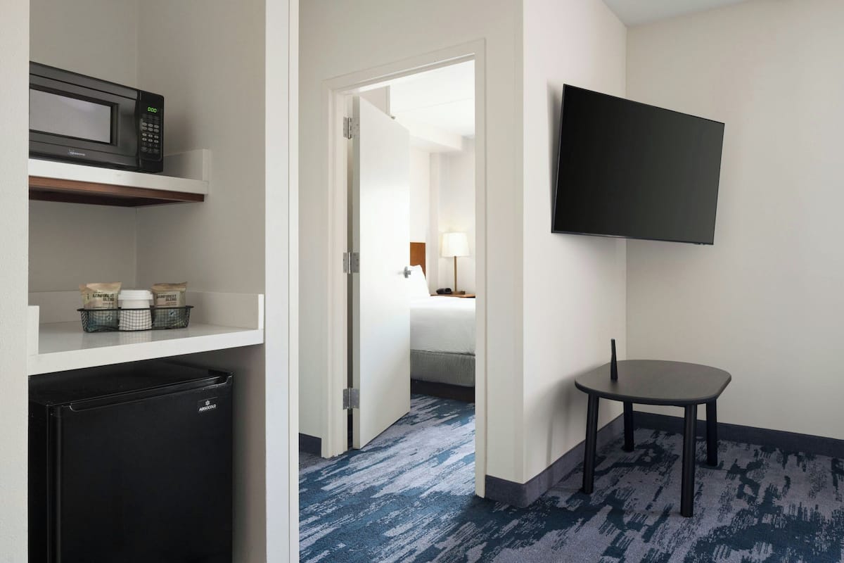 Une chambre d’hôtel équipée d’un four à micro-ondes, d’un réfrigérateur et d’un téléviseur à écran plat fixé au mur.