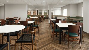 A spacious dining area with multiple tables and chairs, a patterned floor, and framed artwork on the walls.