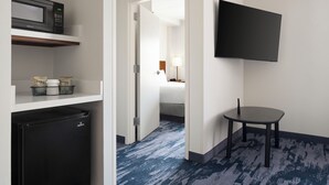A hotel room with a microwave, refrigerator, and a flat-screen TV mounted on the wall.
