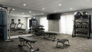 A gym with treadmills, weight benches, dumbbells, and exercise balls.