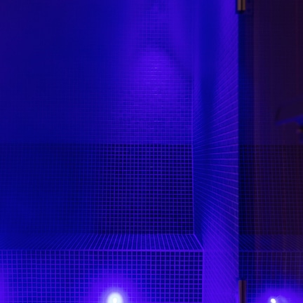 A tiled wall with a grid pattern and a single light source at the top.