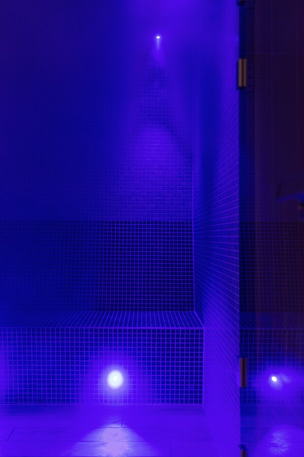 Un mur recouvert de carreaux disposés en motif quadrillé, avec une seule source de lumière en haut.