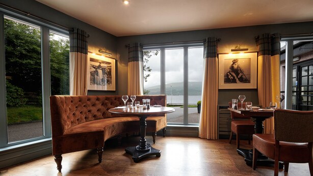 A room with a sofa, a round table, and chairs, with large windows offering a view of the outdoors. - Loch Fyne Hotel And Spa (Inveraray)