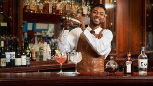 A bartender preparing a drink at a bar with a variety of bottles in the background. - Loch Fyne Hotel And Spa (Inveraray)