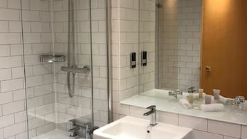 A modern bathroom with a glass shower enclosure, a white sink, and a large mirror reflecting the room.