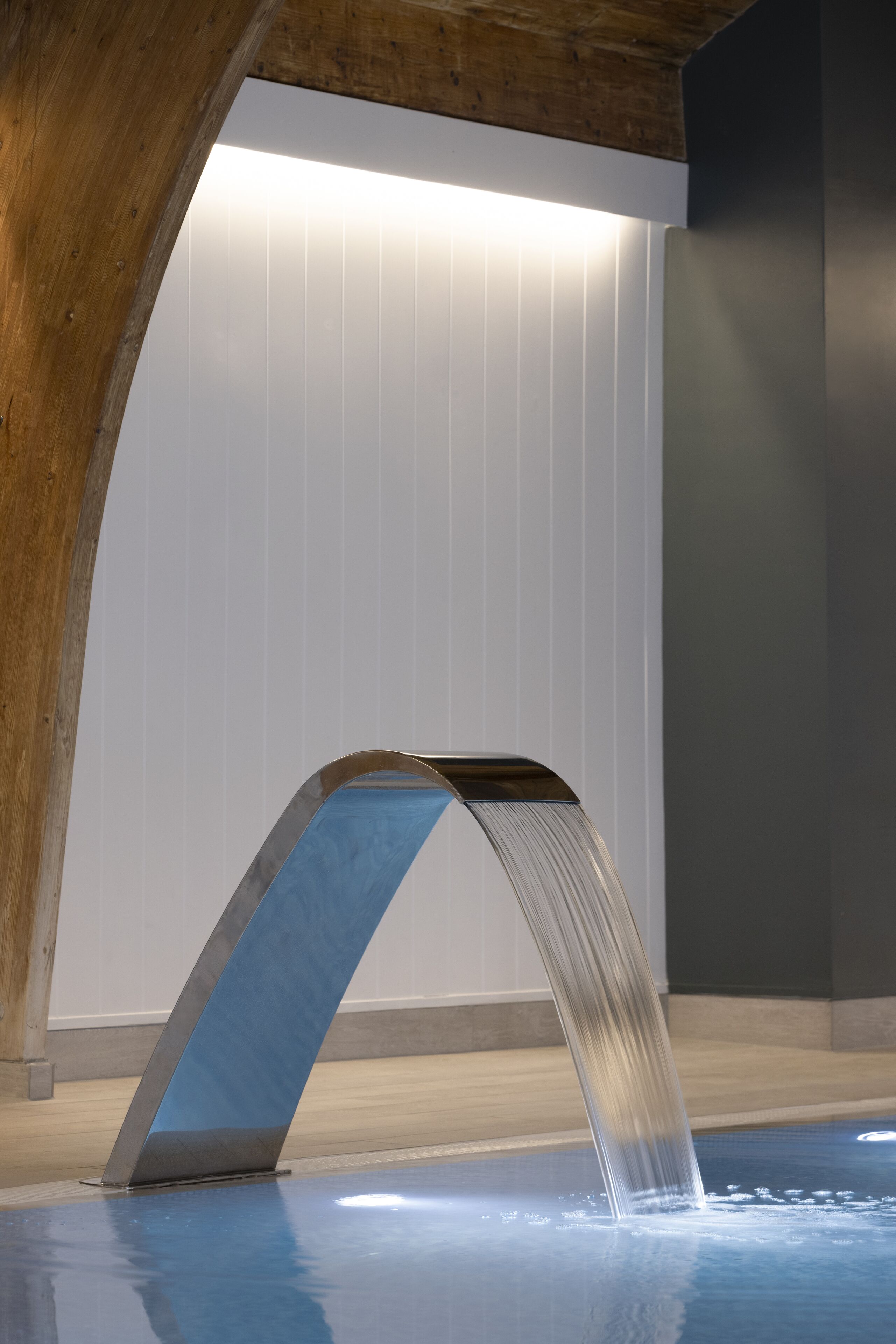 A modern indoor pool with a unique water feature.