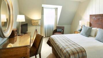 A hotel room with a bed, a desk, a chair, a television, and a large mirror.