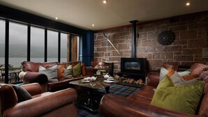 A cozy living room with leather sofas, a coffee table, and a fireplace. - Loch Fyne Hotel And Spa (Inveraray)