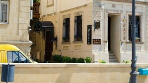 A building with a cafe sign, a yellow car parked in front, and a staircase leading to the entrance. - Old City Inn Hotel (Baku)