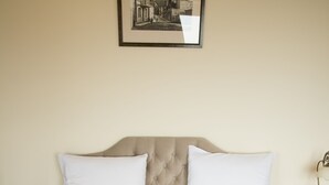 A neatly made bed with a patterned bedspread, two white pillows, and two folded towels on the bed. - Old City Inn Hotel (Baku)
