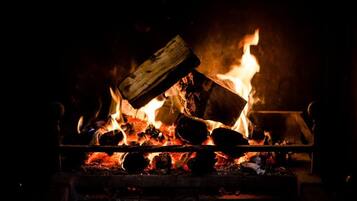 A fireplace with burning logs and a wooden plank.