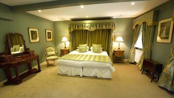 A bedroom with a large bed, two bedside tables, a dresser, a chair, and a mirror.