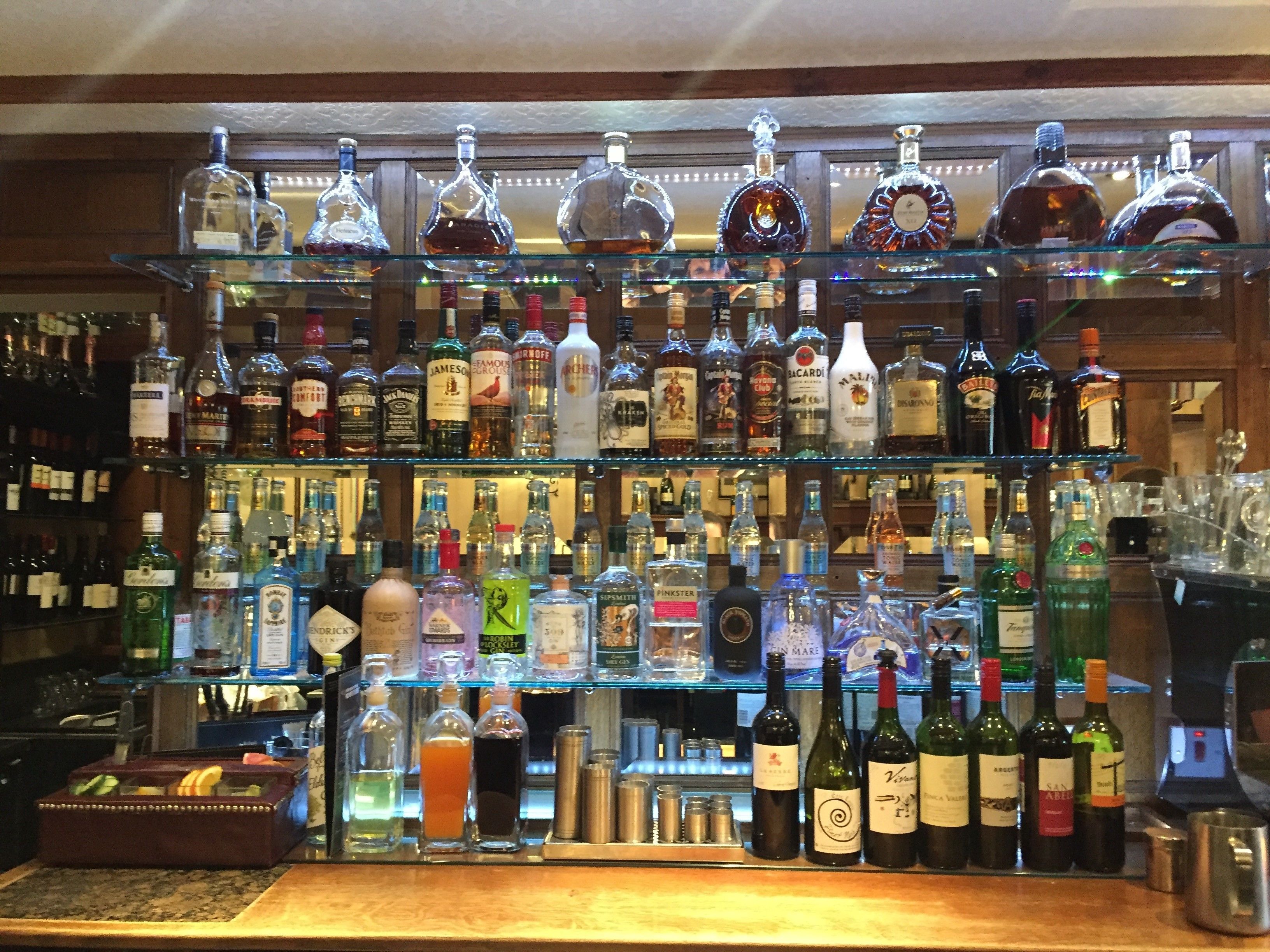 Eine Bar mit mehreren Regalen, gefüllt mit verschiedenen Spirituosenflaschen.