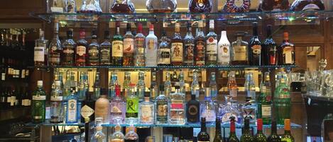 A bar with multiple shelves stocked with various liquor bottles.