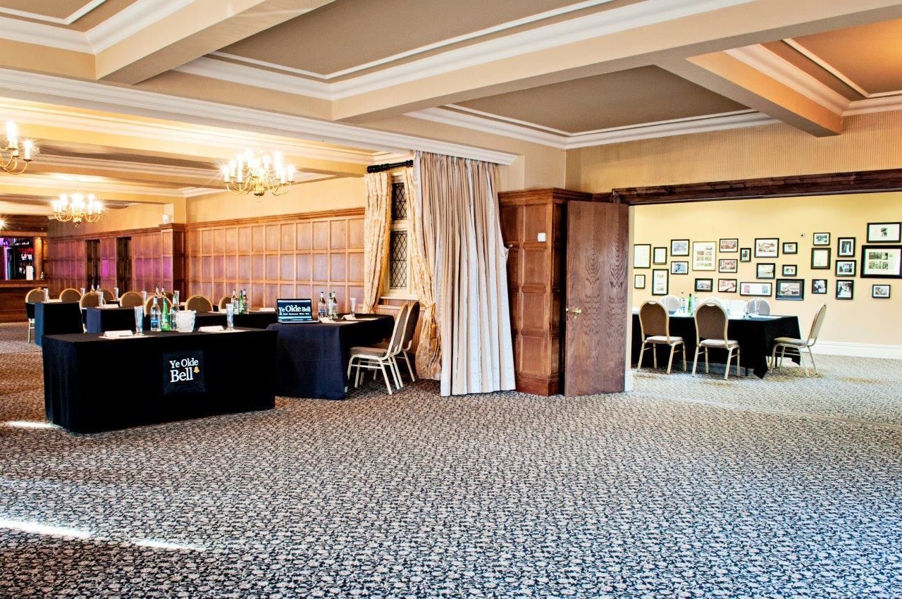A conference room with a black table labeled "Ye Olde Bell" and a wall adorned with framed pictures.