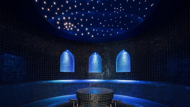Un spa con techo estrellado, tres ventanas arqueadas y una zona circular con hidromasaje.