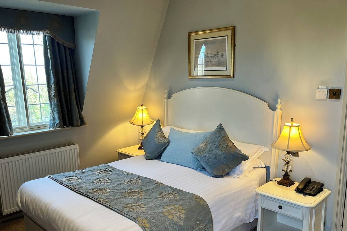 A neatly made bed with a floral bedspread, two bedside lamps, and a framed picture on the wall.
