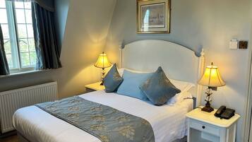 A neatly made bed with a floral bedspread, two bedside lamps, and a framed picture on the wall.
