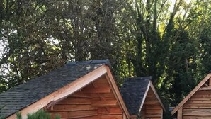 Un espacio de descanso al aire libre con estilo de cabaña, chimeneas y macetas de madera.