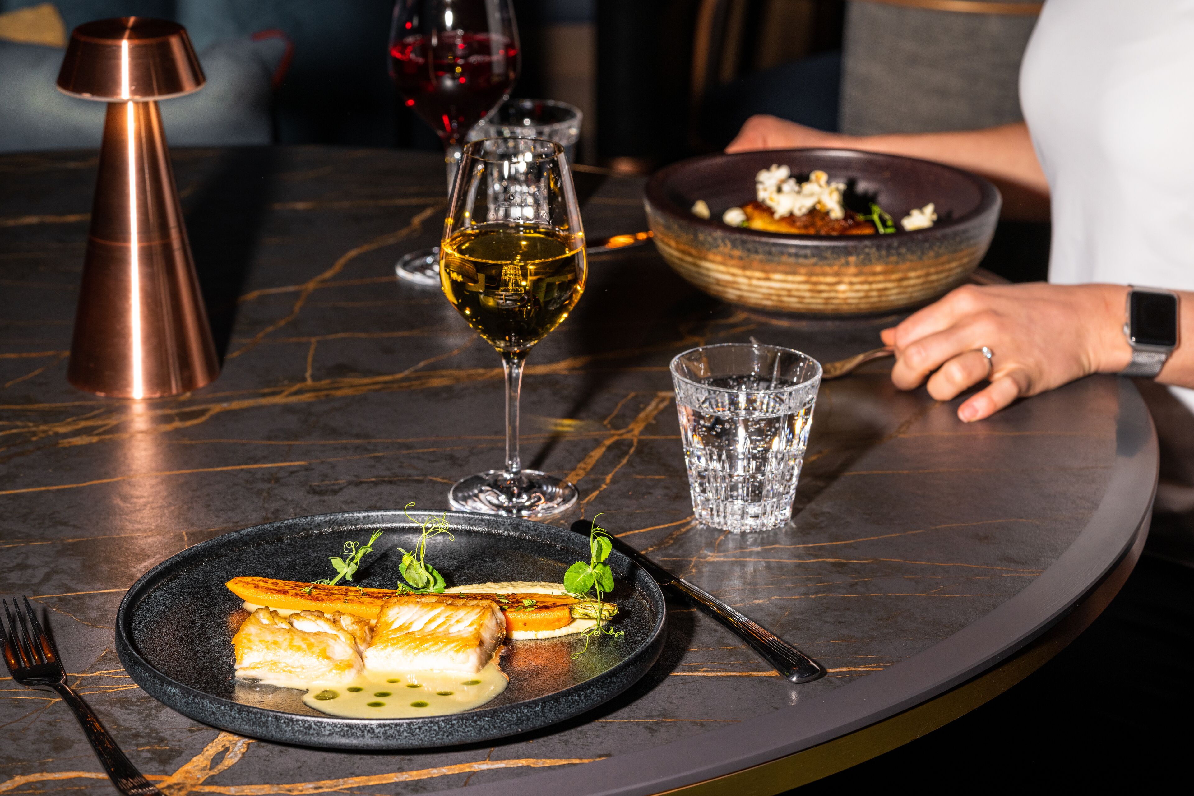 A dining table with a plate of food, a glass of wine, and a candle.
